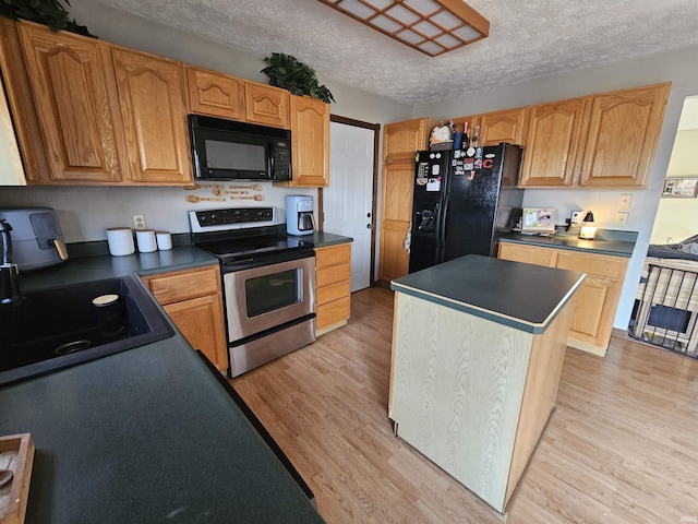 kitchen featuring sink, light hardwood / wood-style flooring, black appliances, and a center island