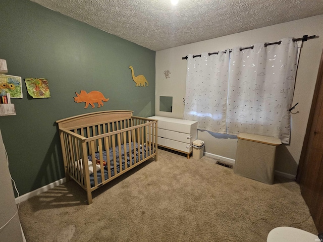 carpeted bedroom with a crib and a textured ceiling