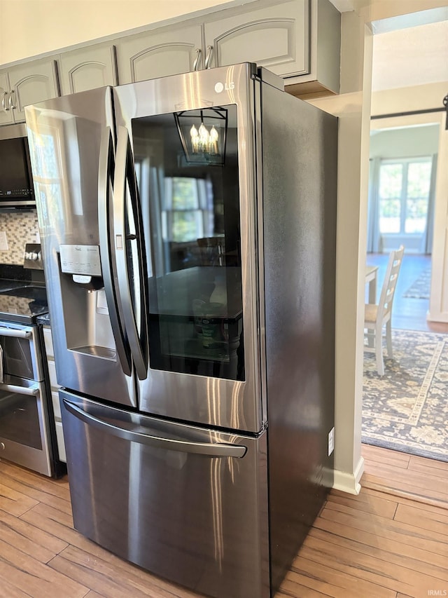 kitchen featuring backsplash, appliances with stainless steel finishes, light hardwood / wood-style floors, and gray cabinetry