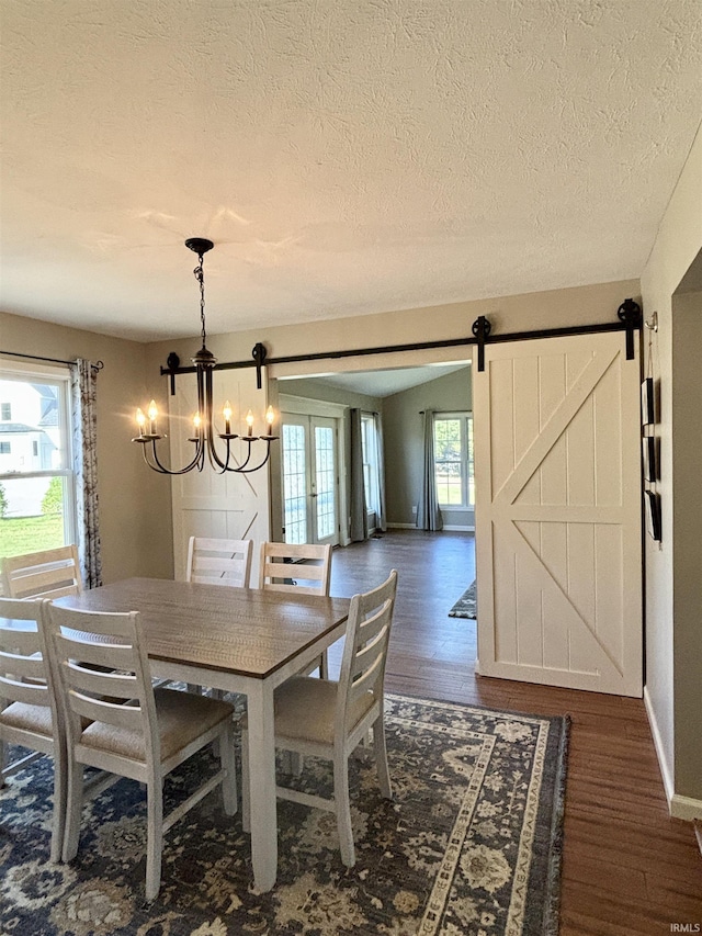 dining room with a barn door, dark hardwood / wood-style floors, an inviting chandelier, and plenty of natural light