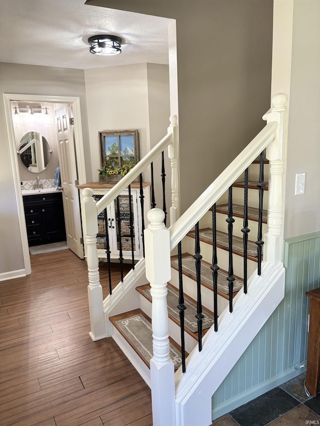 stairway featuring wood-type flooring and sink