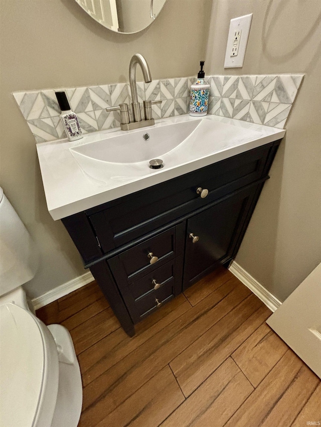 bathroom featuring vanity, toilet, hardwood / wood-style floors, and decorative backsplash