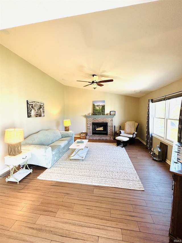 living room with a fireplace, hardwood / wood-style flooring, vaulted ceiling, and ceiling fan