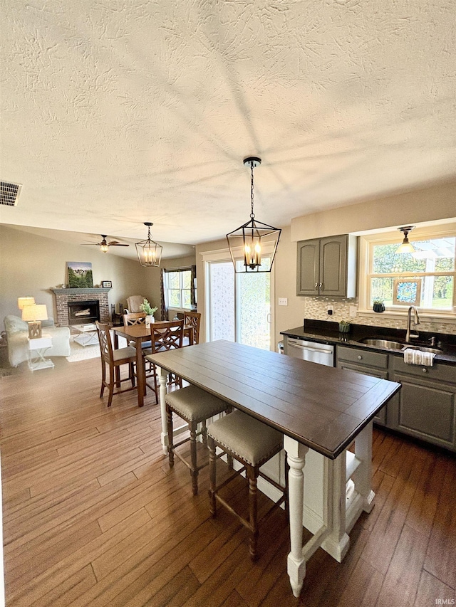 kitchen with sink, tasteful backsplash, decorative light fixtures, dark hardwood / wood-style floors, and a fireplace