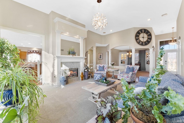 carpeted living room with decorative columns and a chandelier