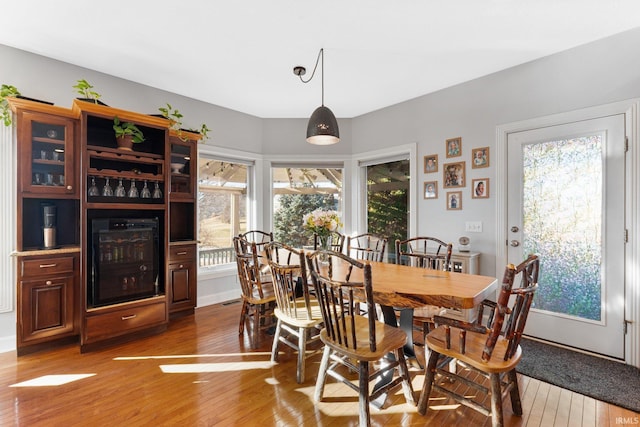 dining space with hardwood / wood-style flooring, a wealth of natural light, and wine cooler