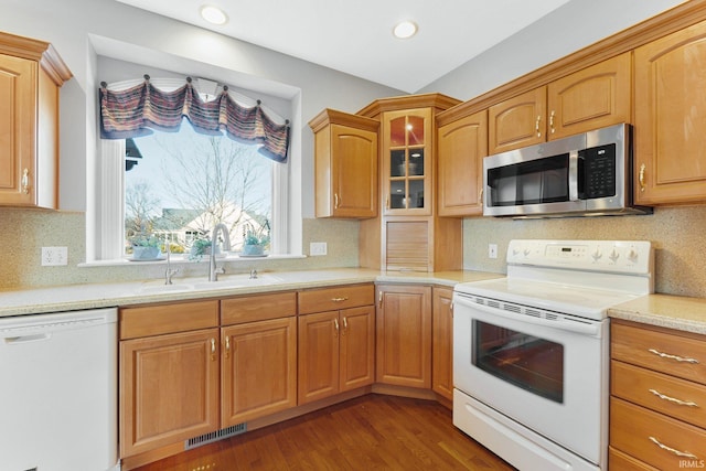 kitchen with sink, backsplash, light stone counters, dark wood-type flooring, and white appliances