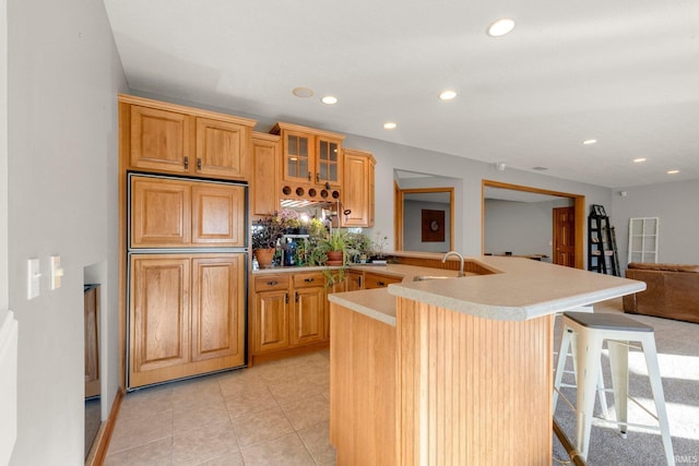 kitchen featuring light tile patterned flooring, sink, a kitchen breakfast bar, paneled built in refrigerator, and kitchen peninsula