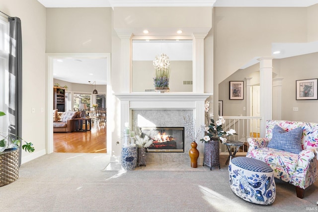 sitting room with decorative columns, a premium fireplace, and light colored carpet