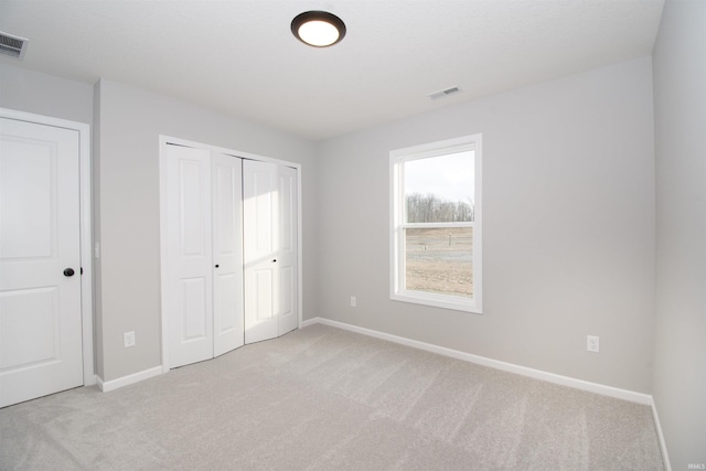 unfurnished bedroom featuring light carpet and a closet