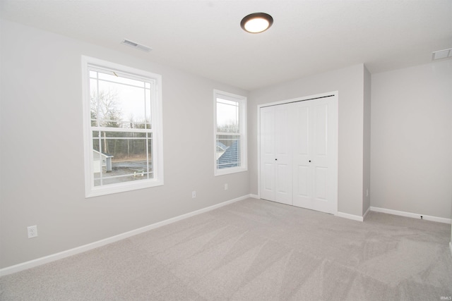 unfurnished bedroom featuring light colored carpet and a closet