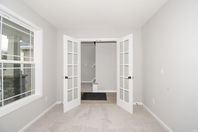 carpeted spare room featuring a barn door and french doors