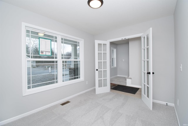 carpeted spare room featuring french doors