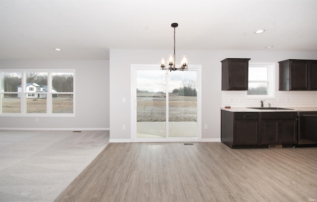 kitchen with sink, tasteful backsplash, dark brown cabinets, dishwasher, and pendant lighting