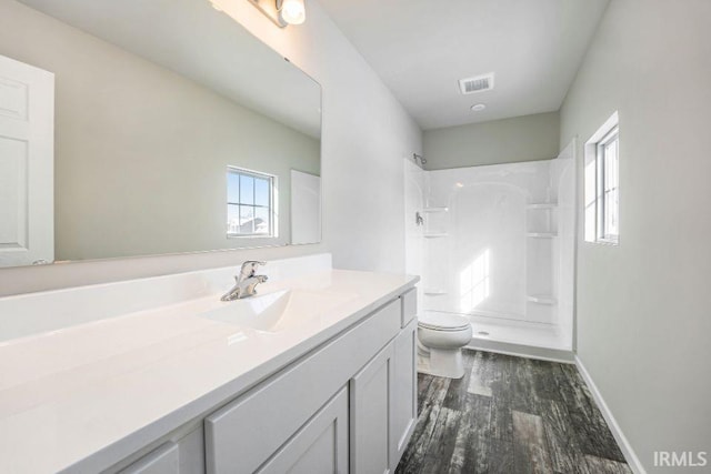 bathroom with walk in shower, vanity, toilet, and a wealth of natural light