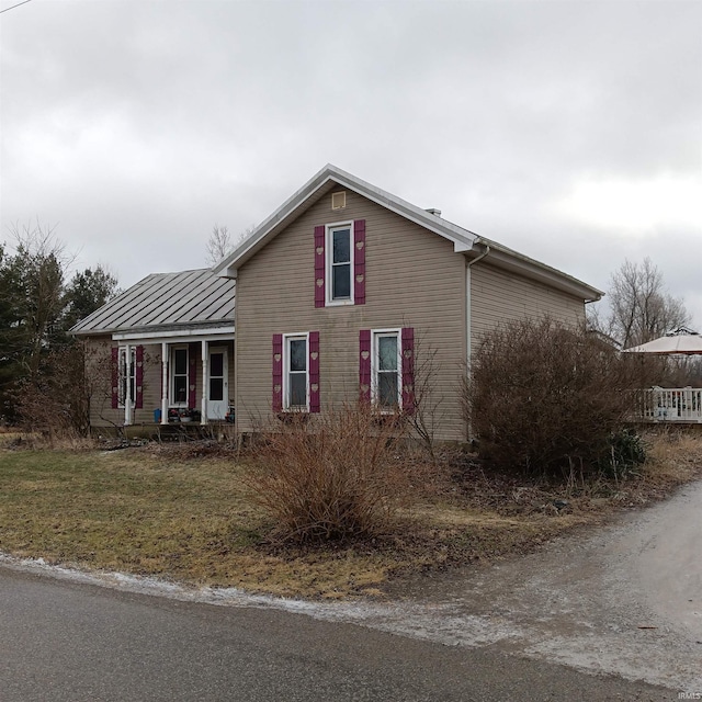 view of side of property with covered porch and a lawn