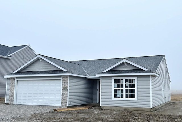 view of front of property featuring a garage, driveway, and a shingled roof