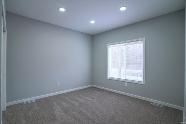 spare room featuring dark colored carpet