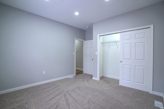 unfurnished bedroom with light colored carpet and a closet