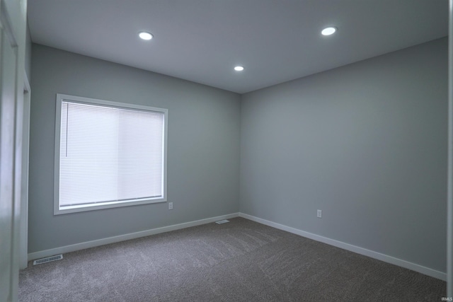 unfurnished room with dark colored carpet