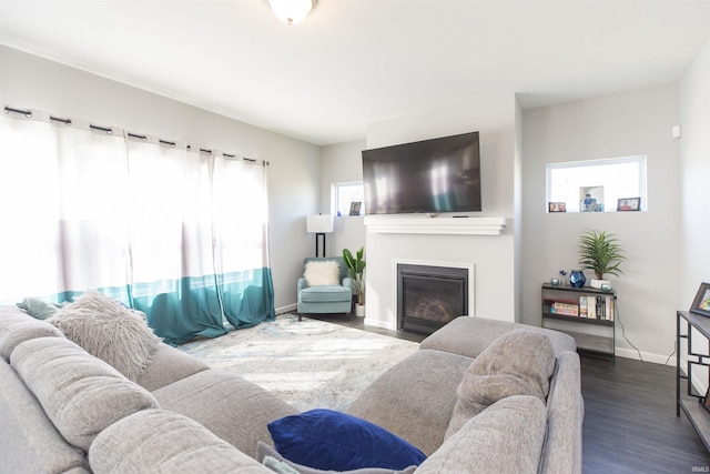 living room featuring baseboards, dark wood-style flooring, and a glass covered fireplace