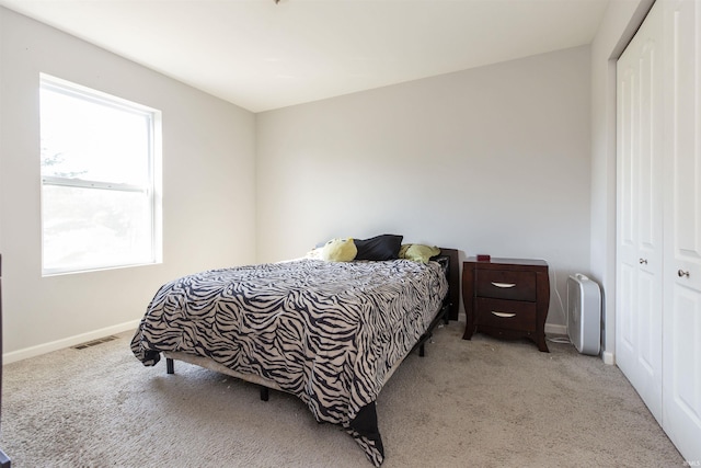 bedroom featuring a closet, light colored carpet, visible vents, and baseboards