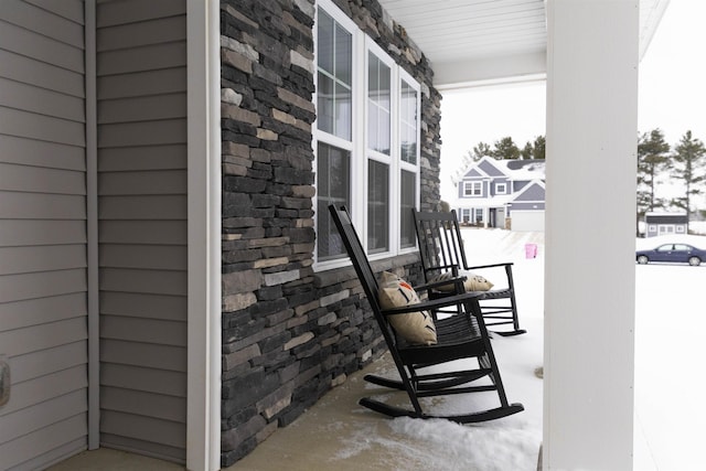 snow covered back of property featuring covered porch