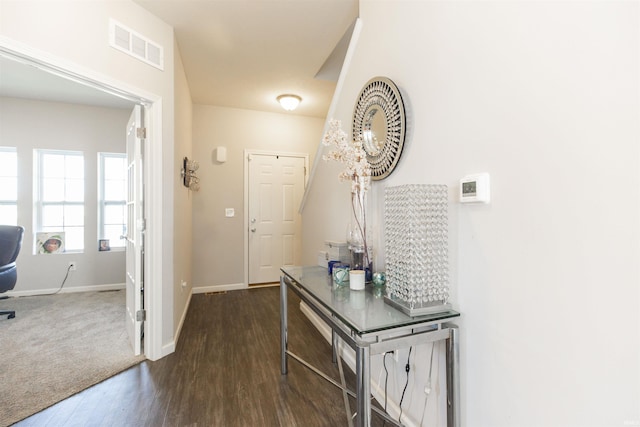 interior space with baseboards, visible vents, and dark wood-style flooring