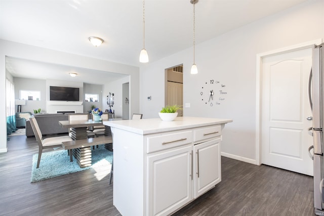 kitchen with a kitchen island, stainless steel refrigerator, decorative light fixtures, white cabinets, and dark hardwood / wood-style flooring