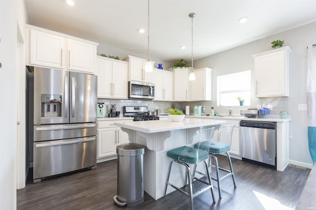 kitchen featuring white cabinets, a kitchen island, stainless steel appliances, light countertops, and pendant lighting