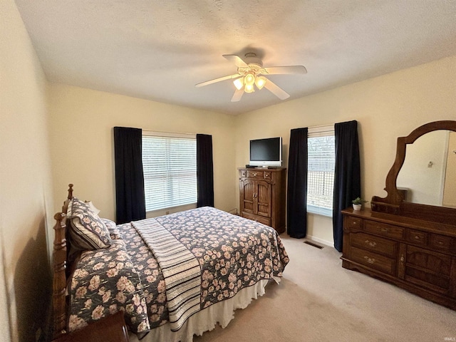 bedroom with light colored carpet, a textured ceiling, and ceiling fan