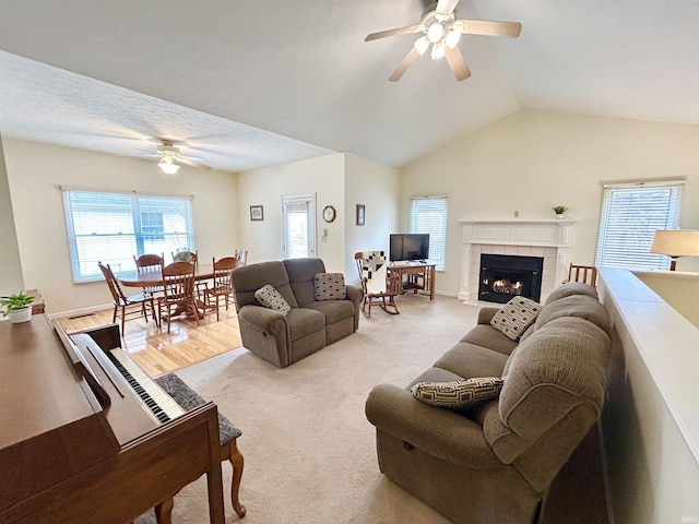 living room with lofted ceiling, a tiled fireplace, light carpet, and ceiling fan