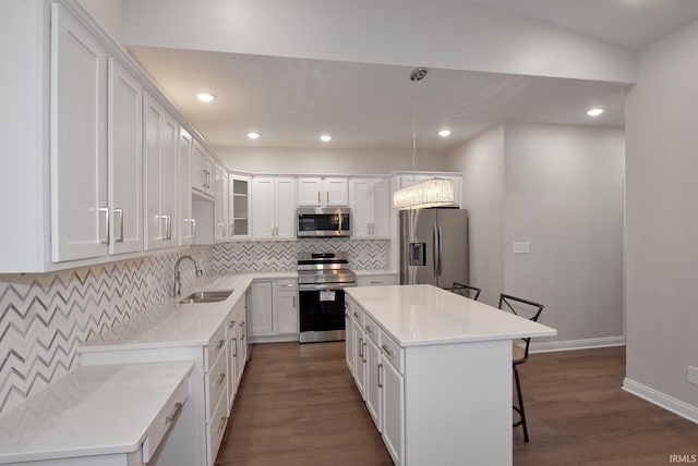 kitchen featuring sink, white cabinetry, a center island, appliances with stainless steel finishes, and pendant lighting