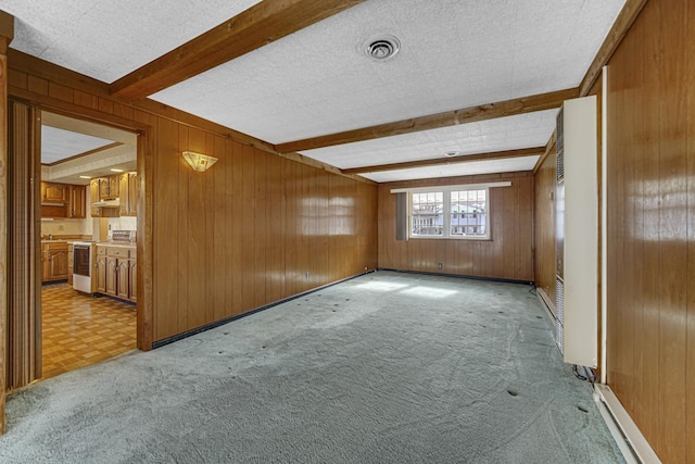 bonus room featuring light colored carpet, beam ceiling, a textured ceiling, and wood walls