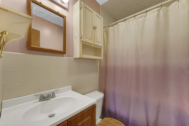 bathroom with vanity, toilet, curtained shower, and tile walls