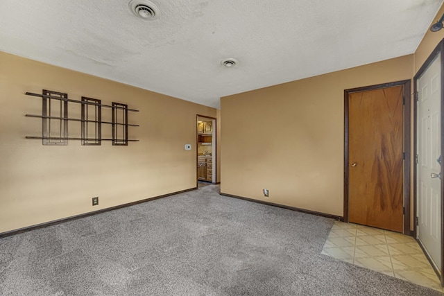 carpeted empty room featuring a textured ceiling