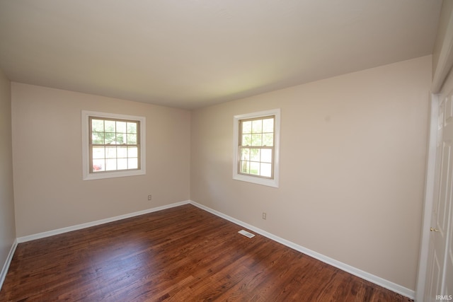 empty room featuring a healthy amount of sunlight and dark hardwood / wood-style floors