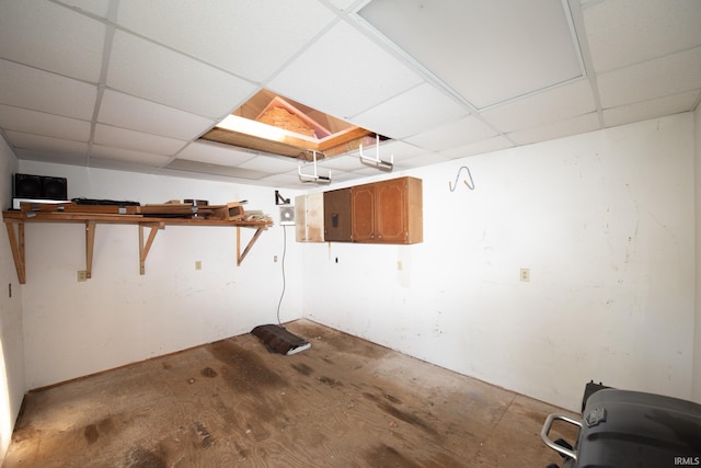 basement featuring a paneled ceiling and electric panel