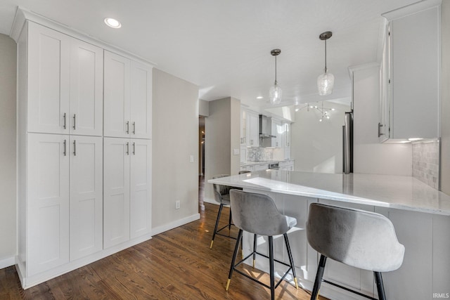 kitchen with a kitchen bar, white cabinetry, kitchen peninsula, pendant lighting, and backsplash