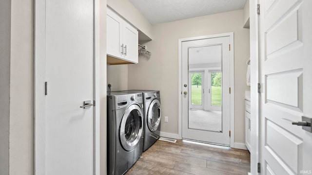 laundry room featuring cabinets, wood-type flooring, separate washer and dryer, and a textured ceiling