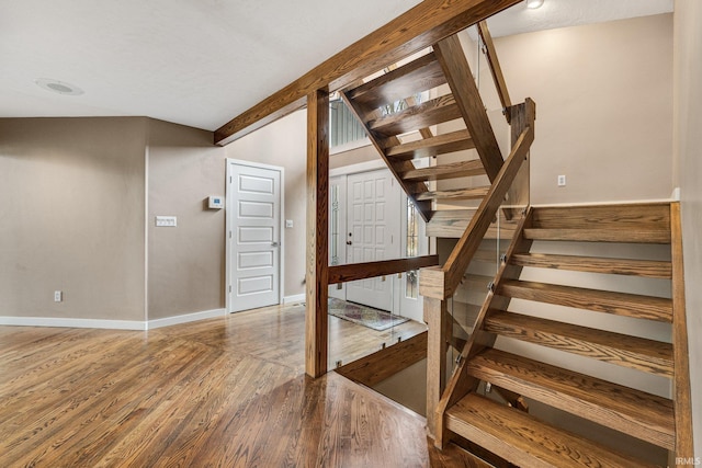 stairs featuring hardwood / wood-style flooring and beam ceiling