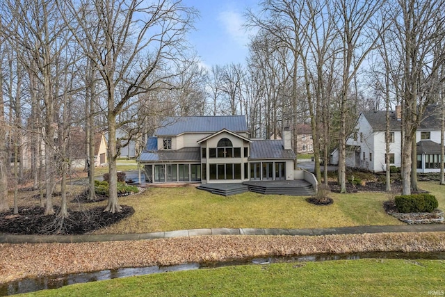 rear view of house featuring a yard and a sunroom