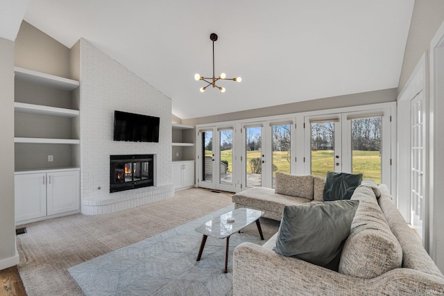 living room featuring french doors, plenty of natural light, a brick fireplace, and built in features