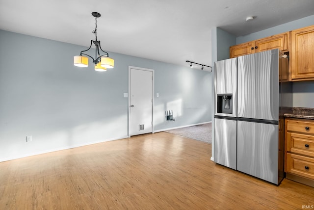 kitchen with rail lighting, stainless steel fridge, a chandelier, hanging light fixtures, and light hardwood / wood-style flooring