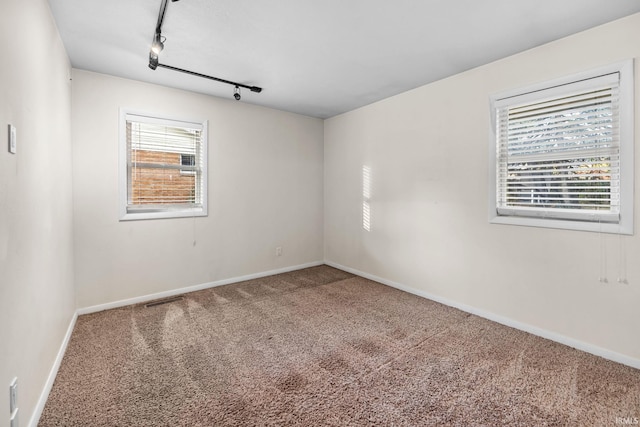 empty room featuring carpet and track lighting