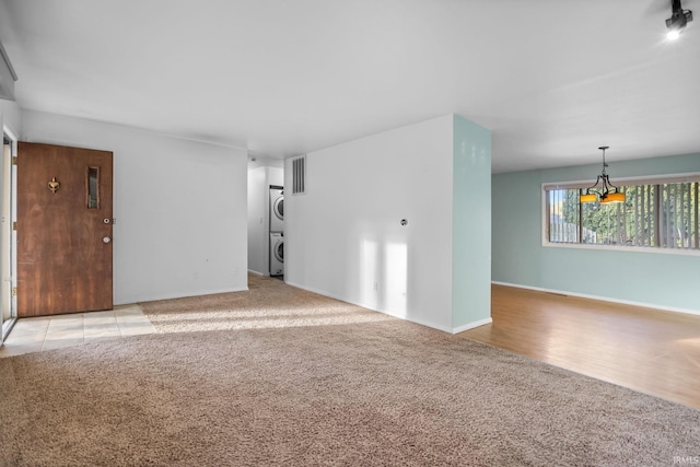 carpeted spare room with stacked washer and dryer