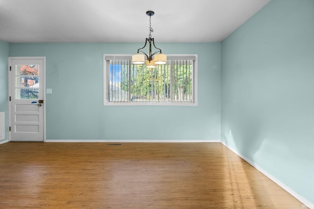 unfurnished dining area featuring hardwood / wood-style flooring and a chandelier