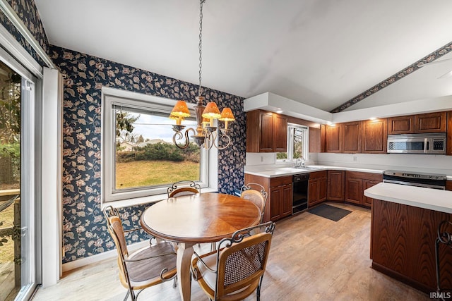 kitchen featuring lofted ceiling, sink, decorative light fixtures, light wood-type flooring, and stainless steel appliances