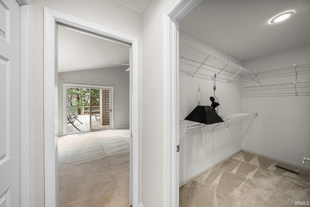 spacious closet with lofted ceiling and light carpet