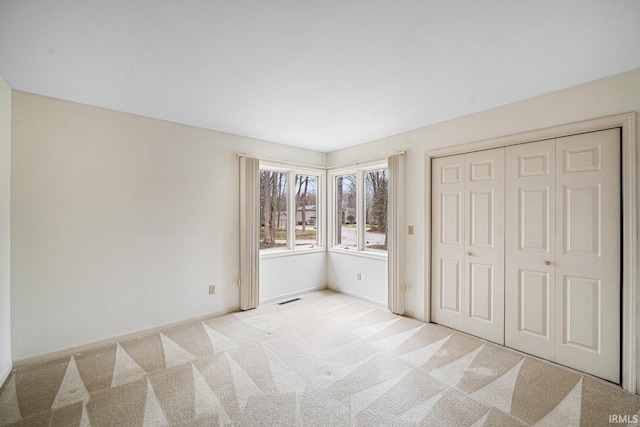 unfurnished bedroom featuring light colored carpet and a closet